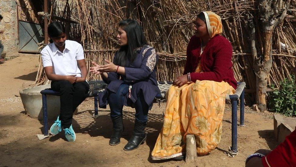 Ajaita Shah (C) trying to persuade a villager that solar alternatives are a more reliable solution to the lack of regular electricity.