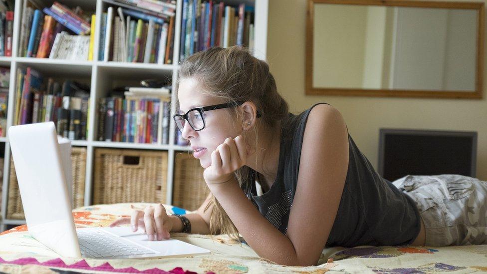 A teenage girl looking at her laptop