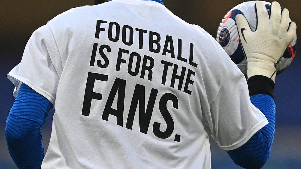 A Brighton player wears a t-shirt with the slogan 'Football is for the fans' on the back in protest against the proposed European Super League before a match against Chelsea