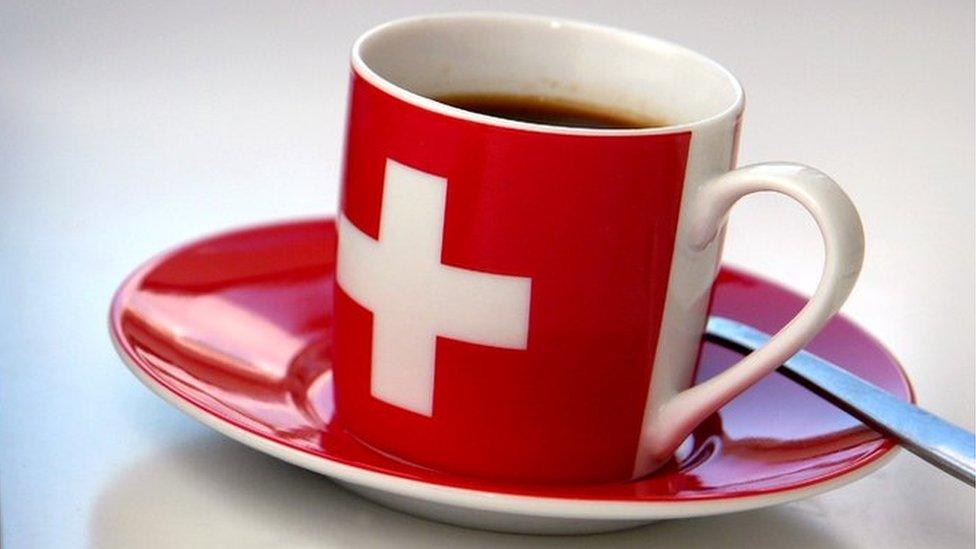 A cup of coffee with the Swiss logo