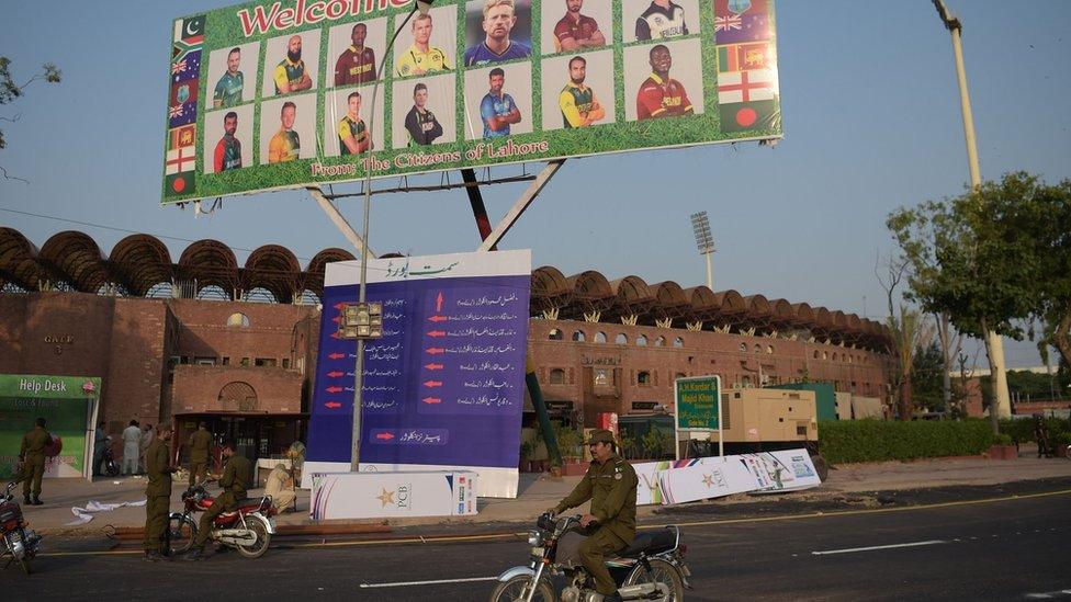 Pakistani policemen ride past a billboard featuring International World XI cricketers displaying outside the Gaddafi Cricket Stadium in Lahore on 10 September 2017