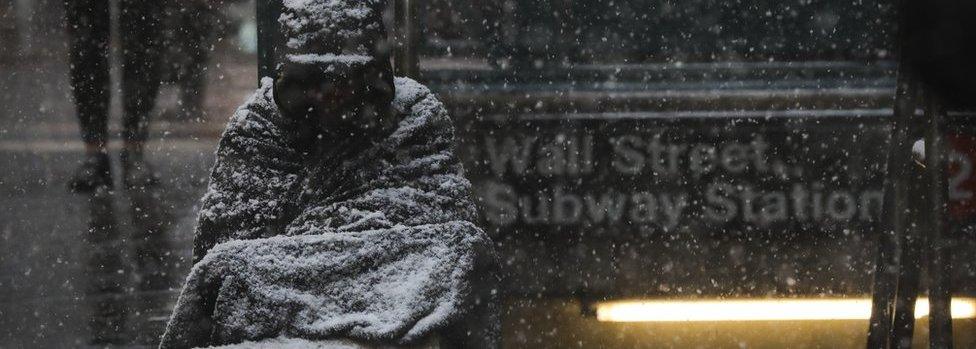 A homeless man sits in the falling snow in the Financial District, January 30, 2019 in New York City.