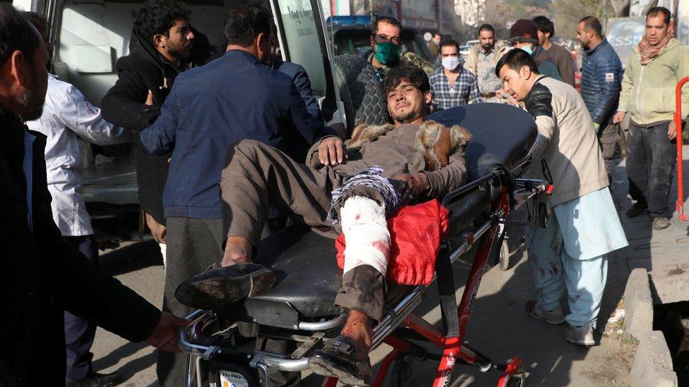 An injured man is carried to a hospital after rockets hit residential areas in Kabul