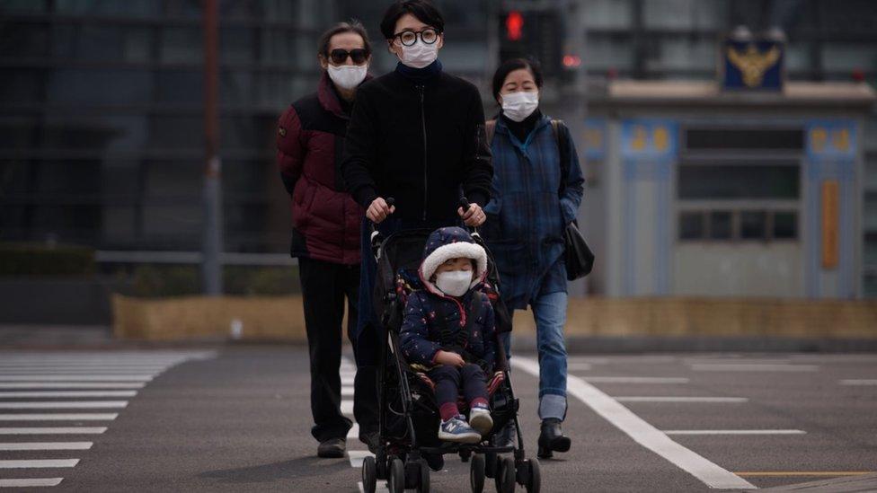 Korean family with little child, all wearing face masks