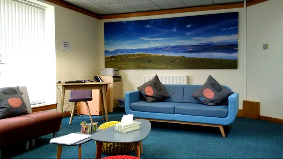 hearing room with bright blue sofas and sea mural on the wall