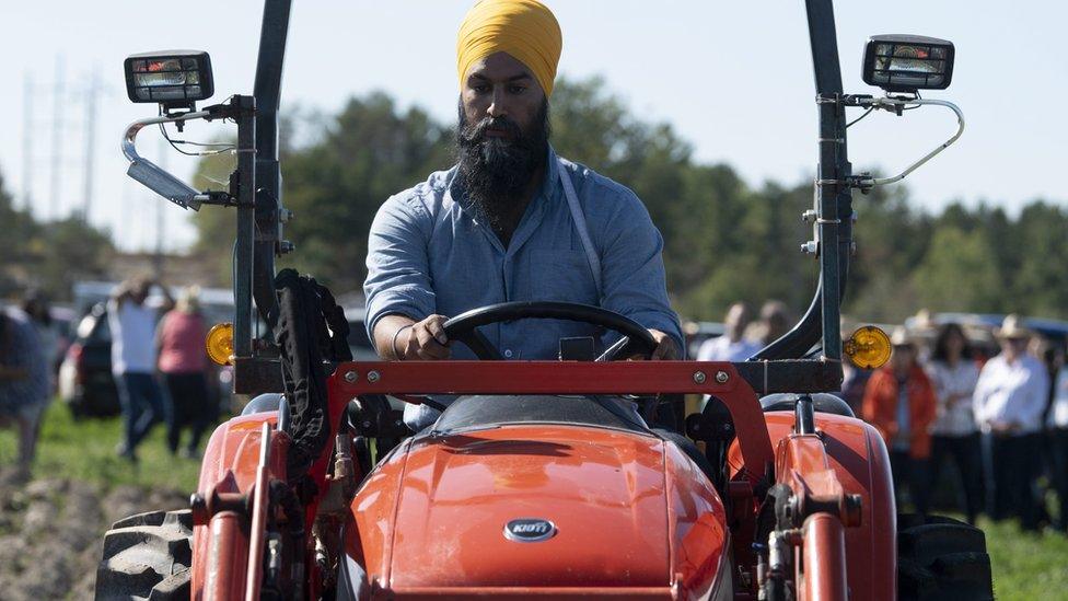 NDP leader Jagmeet Singh drives a tractor as he campaigns in Ontario