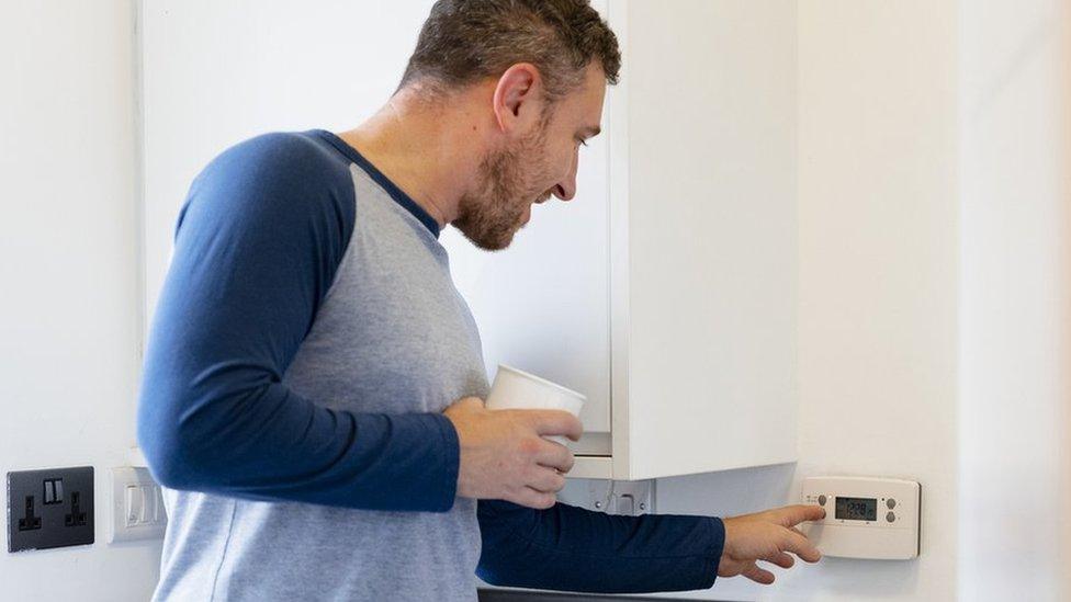 Man turning down thermostat