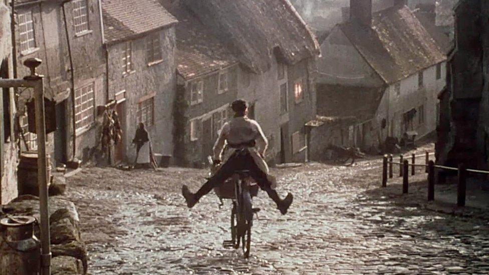 A young Carl Barlow freewheels down the street cobbled street