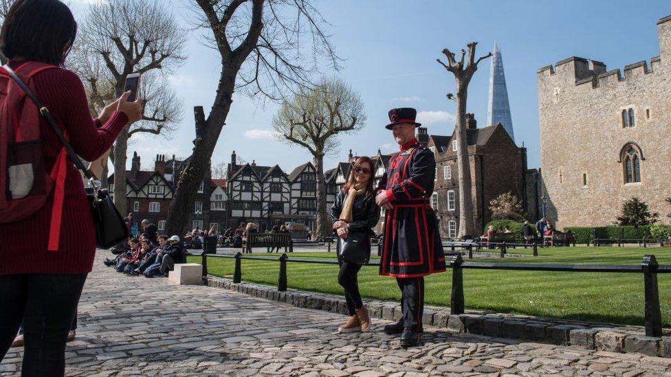 Tourists have photos taken with a Beefeater at the Tower of London