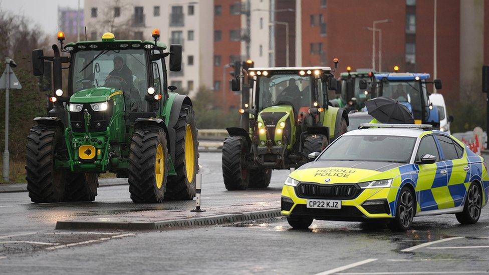 Tractorau yn mynd heibio car heddlu