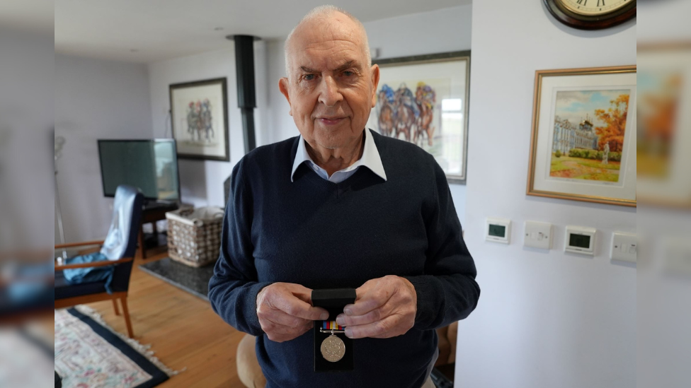 Brian Cantle holding his Nuclear Test Medal