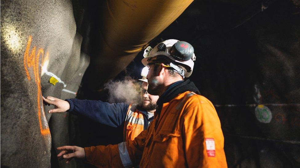 Workers in hard hats underground in the mine at Cononish