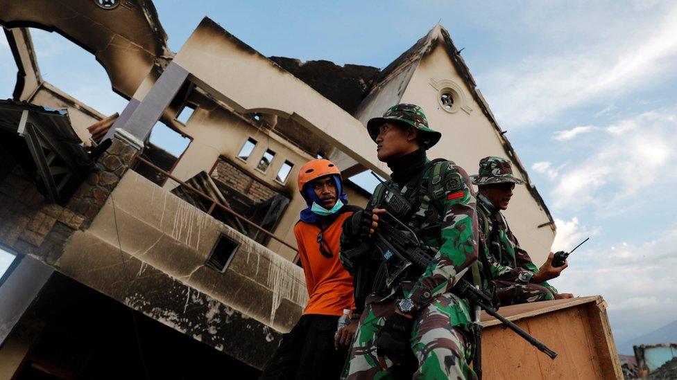 Soldiers and rescue members sit as they take a break from a search to try and find dead bodies from last week's earthquake in the Balaroa neighbourhood in Palu, Sulawesi Island, Indonesia