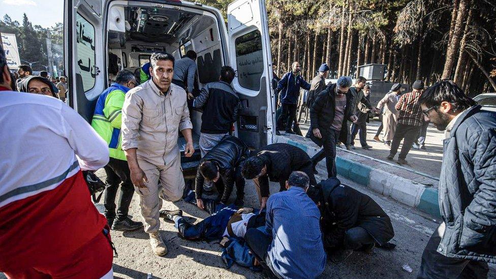 A person wounded by an explosion near Qasem Soleimani's tomb in Kerman, Iran, is treated beside an ambulance (3 January 2023)