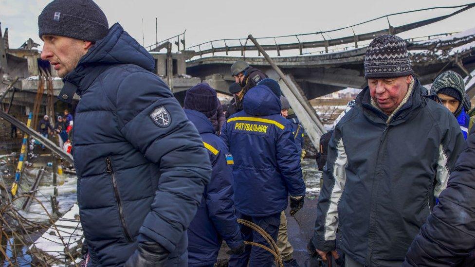 Residents of Irpin seen evacuating away from the frontline through a destroyed bridge under the assistance of the Ukraine police