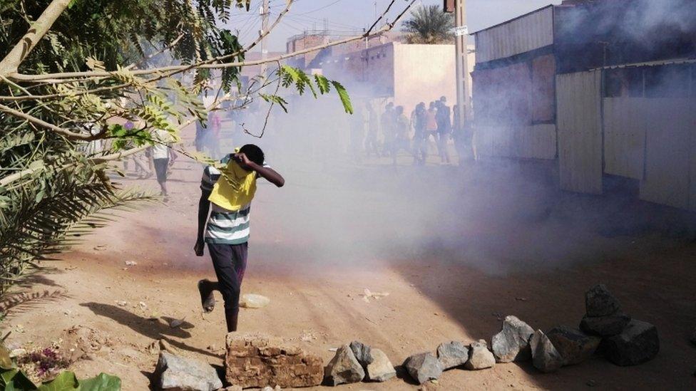 A young man covers his face to protect himself from tear gas during protests in Khartoum in February