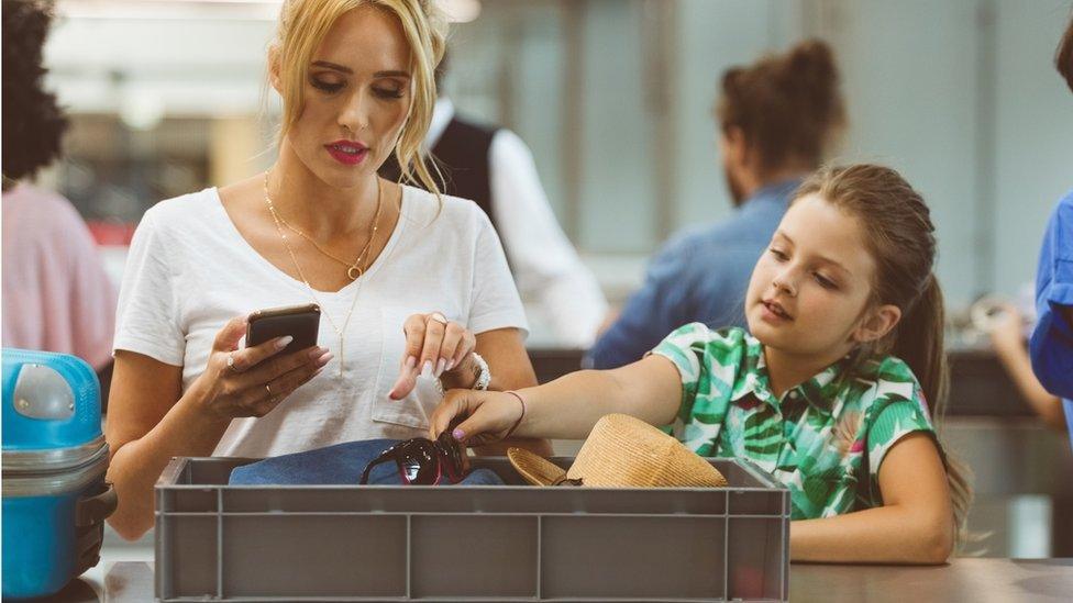 girl-with-mother-going-through-airport-security-checks.