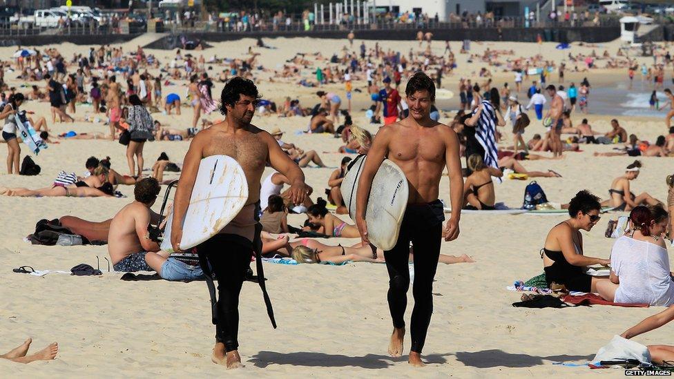 Two surfers walk during a warm weather day at Bondi Beach 31 October 2014