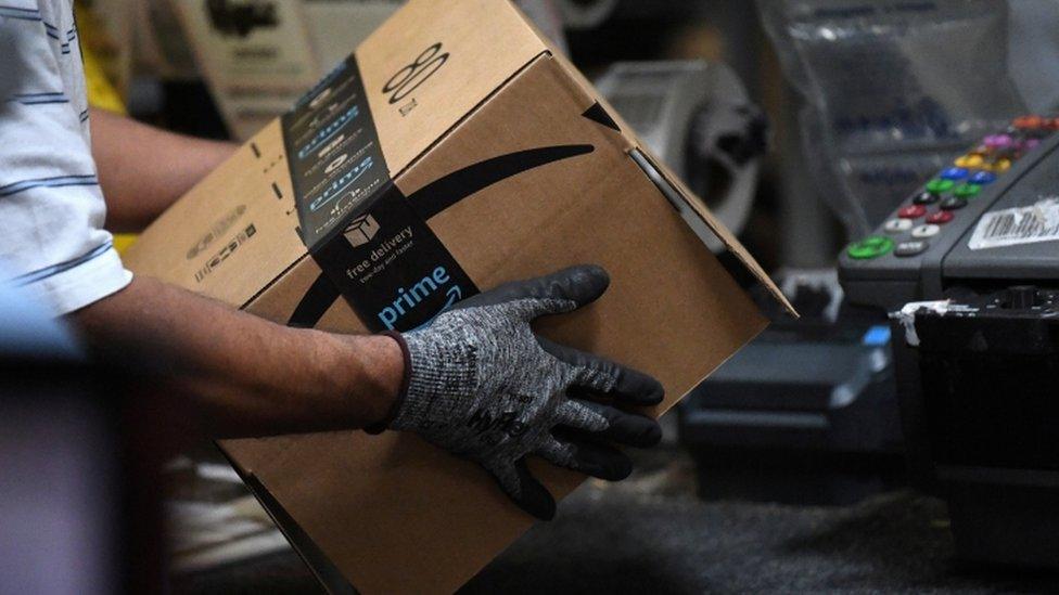 A worker handling a box from Amazon in a factory