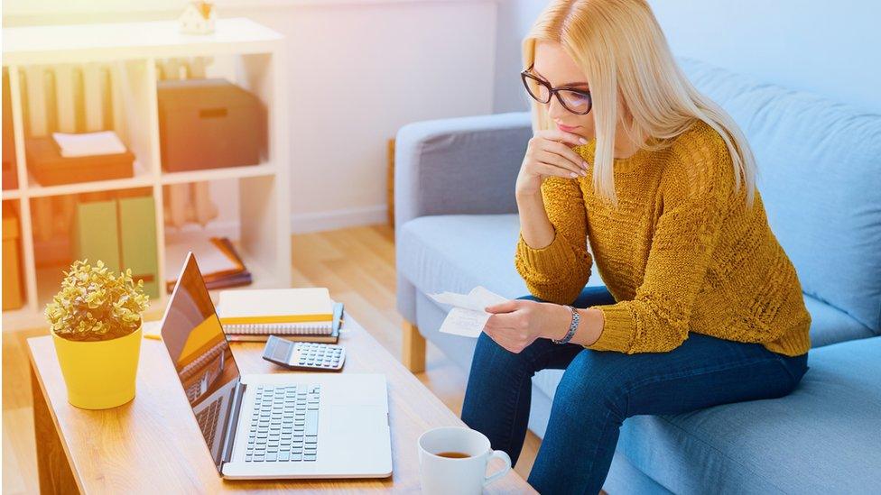 Woman sitting at home counting expenses