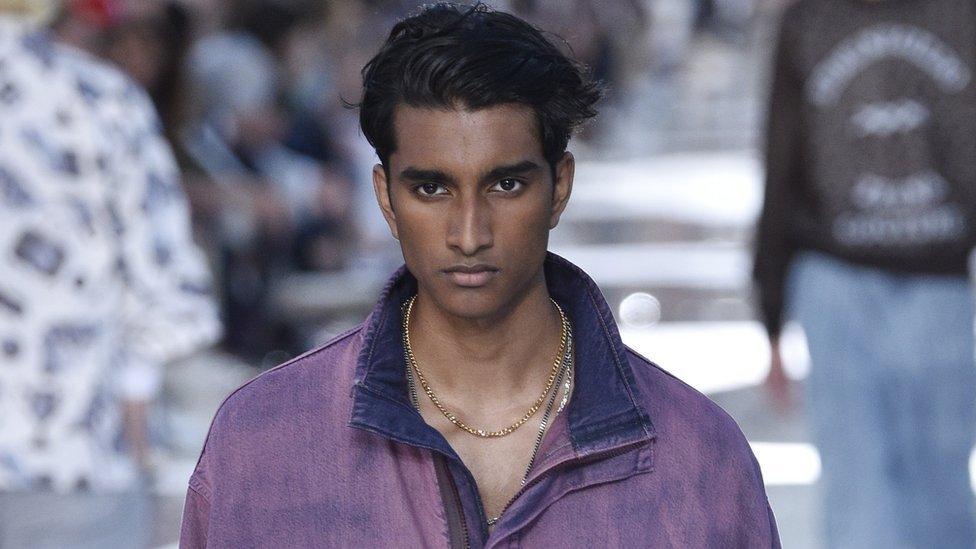 Jeenu Mahadevan in a purple jacket and gold chain, modelling at the Ermenegildo Zegna show at Milan Men's Fashion Week in June 2018