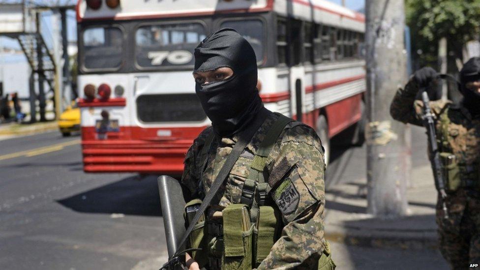 Soldiers of the Reaction Special Forces stand guard near one of the few buses that circulates in San Salvador on 30 July, 2015