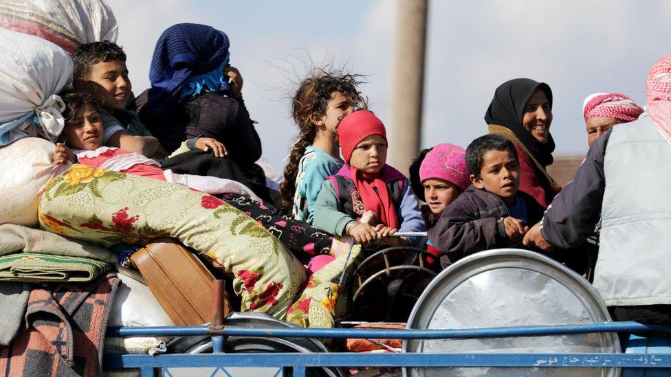 Displaced Syrians sit on a lorry in the town of Inab, in the Afrin region (12 March 2018)