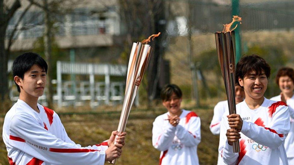 Azusa Iwashimizu passes the Olympic flame to high school student Asato Owada