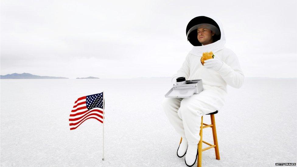 A stock image of an astronaut eating a hamburger