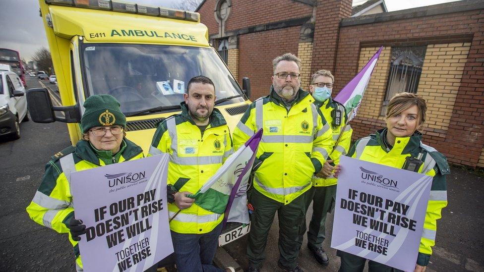 Striking paramedics hold placards and flags as they stand on a picket line