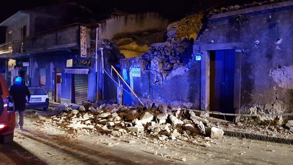 Firemen work in the ruins of a house after an earthquake hit the village of Fleri