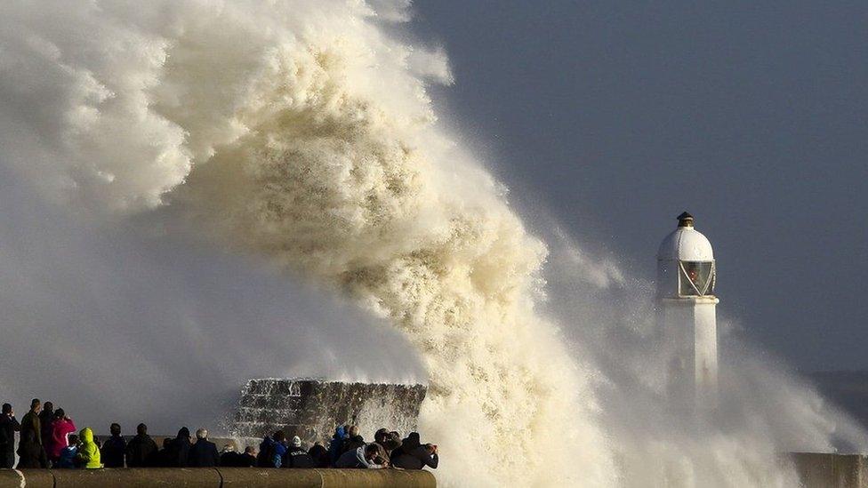 Huge waves crashing into barriers near a lighthouse