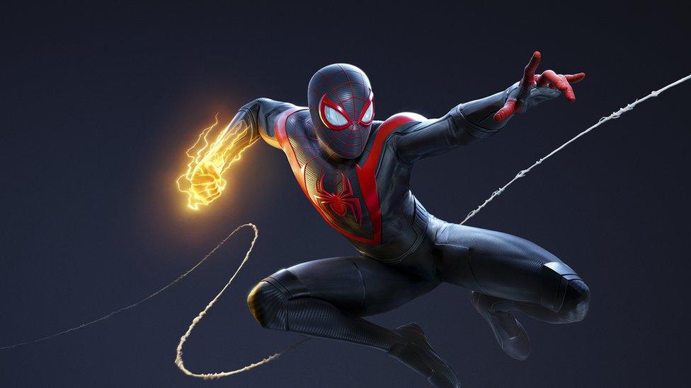 Miles Morales in his black suit shoots a web off screen with a golden electric fist