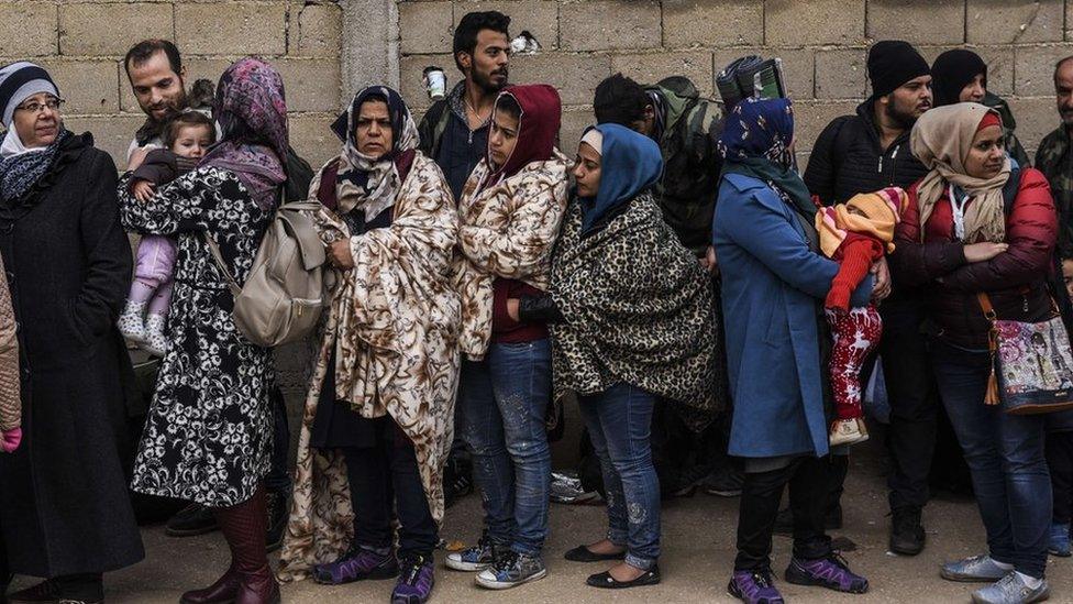 Migrants and refugees wait to board a bus after crossing the Macedonian-Serbian border near the village of Miratovac on October 21, 2015, after crossing the Macedonian-Serbian border