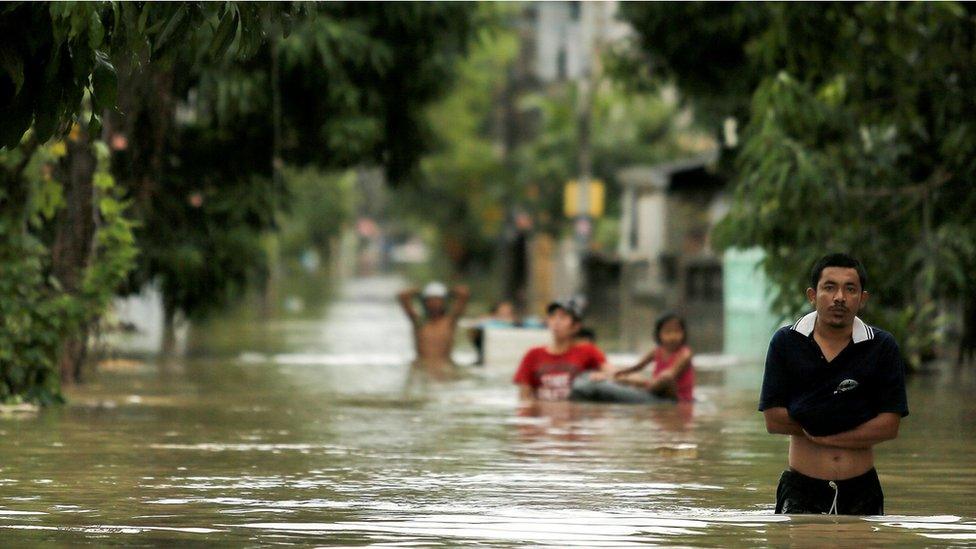 People walk in a flooded street at Muang district in Nakhon Si Thammarat province, southern Thailand, 6 January 2017