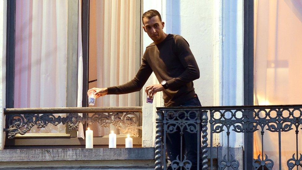 Mohamed Abdeslam lighting candles at the window of the family home during a vigil for the dead in Brussels