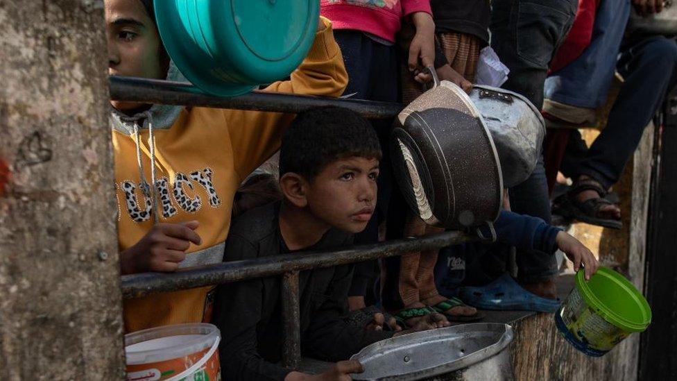 Internally displaced Palestinians gather to collect food donated by a charity group before breakfast, on the fourth day of the holy month of Ramadan in Rafah, southern Gaza Strip, 14 March 2024.