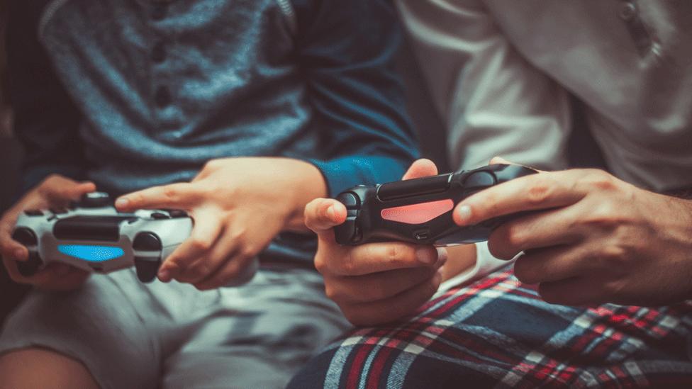 Boy and man holding consoles