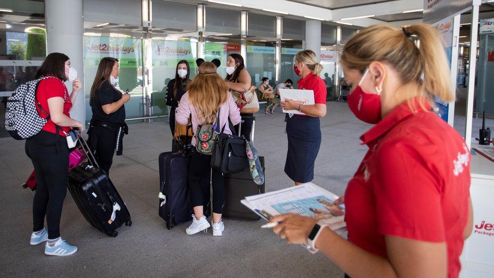 British tourists walk with their luggage outside the airport upon their arrival to Palma de Mallorca on Monday