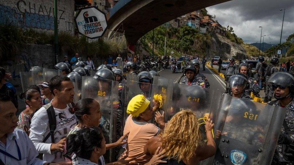 A group of people protest in front of members of the Bolivarian National Police (PNB) in Caracas, Venezuela, 28 December 2017.