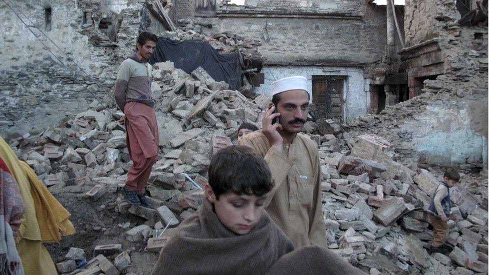 People looking at damaged houses in Afghanistan