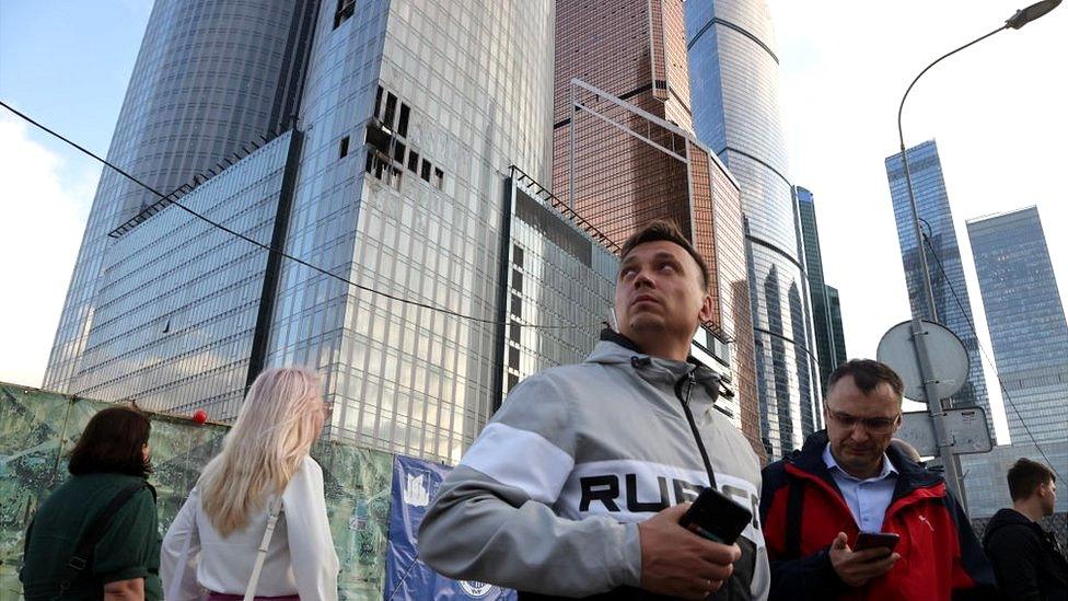 People walk past a damaged building of the Moscow-City business centre on 23 August 2023