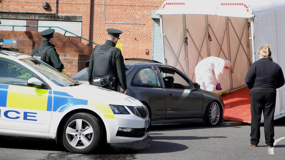 Police officers look on as a grey MG car is driven into a forensic van to be taken away from Belfast City Hospital