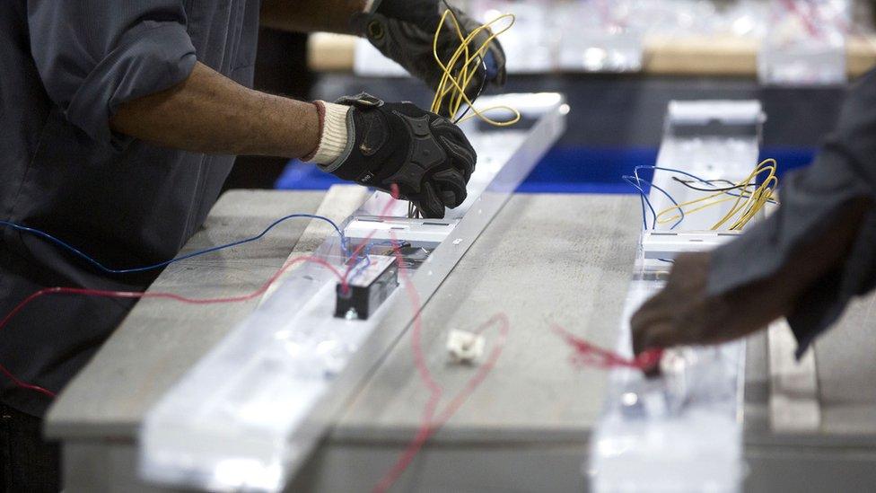 Employees connect ballast wires inside an energy efficient florescent light fixture at a Jessup factory in Maryland