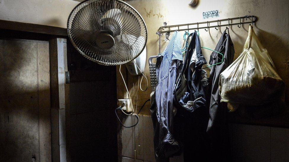 Clothes belonging to a Rohingya refugee hang on hooks in his room in his room off an underground alleyway in Phnom Penh