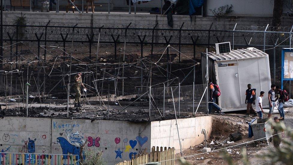 Migrants walk into the burned out area at the Moria camp on the Greek island of Lesbos, September 20, 2016