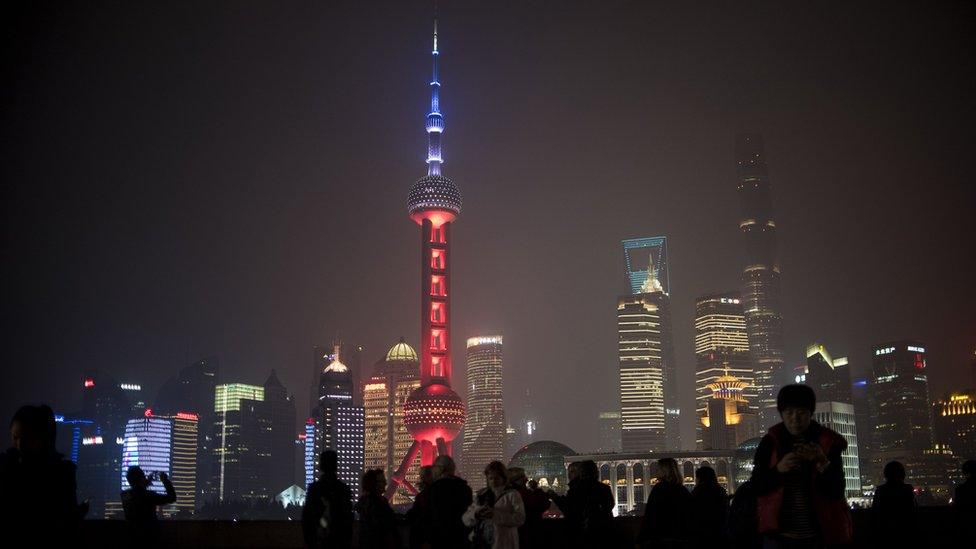 (C), in the Lujiazui Financial District in Pudong, is lit in red, white and blue, resembling the colours of the French flag, in Shanghai on November 14, 2015,