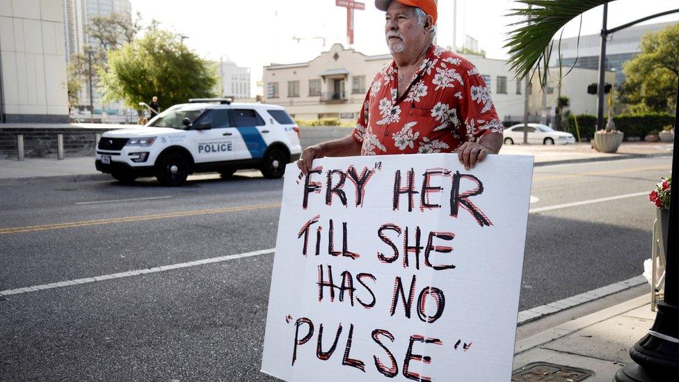 Man with sign against Noor Salman