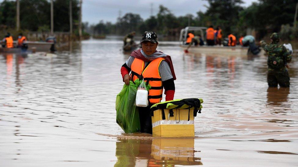 A volunteer wading through a flooded road after the dam collapse in southern Laos