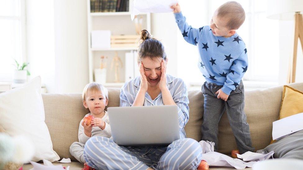 Woman on laptop with two children